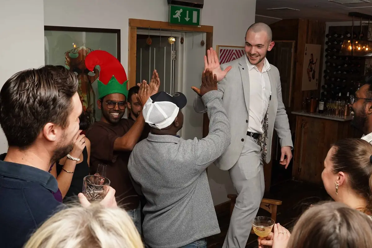 Close-up magician engaging guests at festive office Christmas gathering.