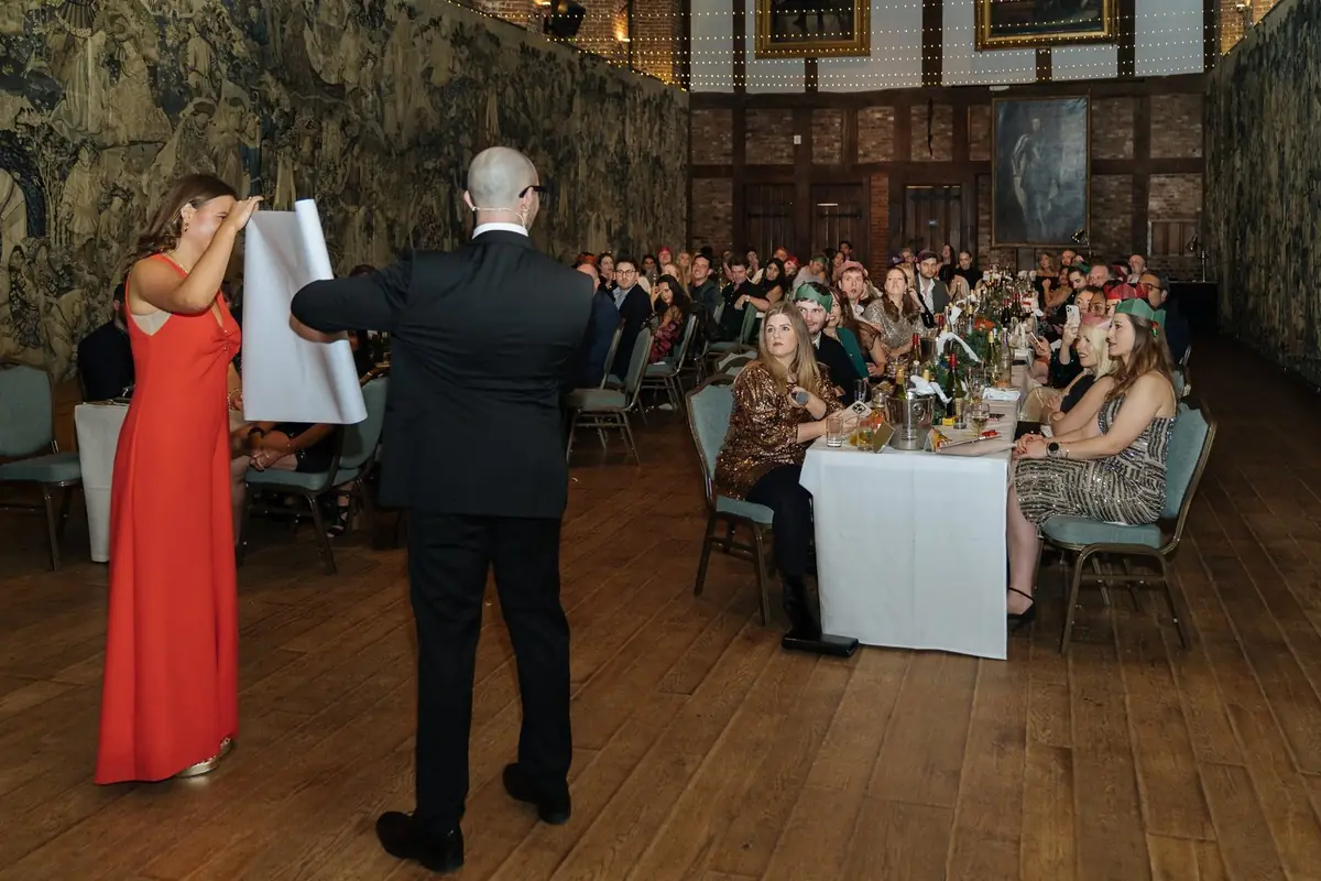Guest assisting a magician during interactive stage magic at corporate party.