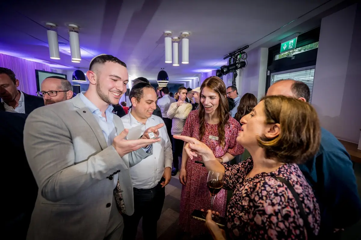Small group of staff laughs while magician performs interactive tricks.