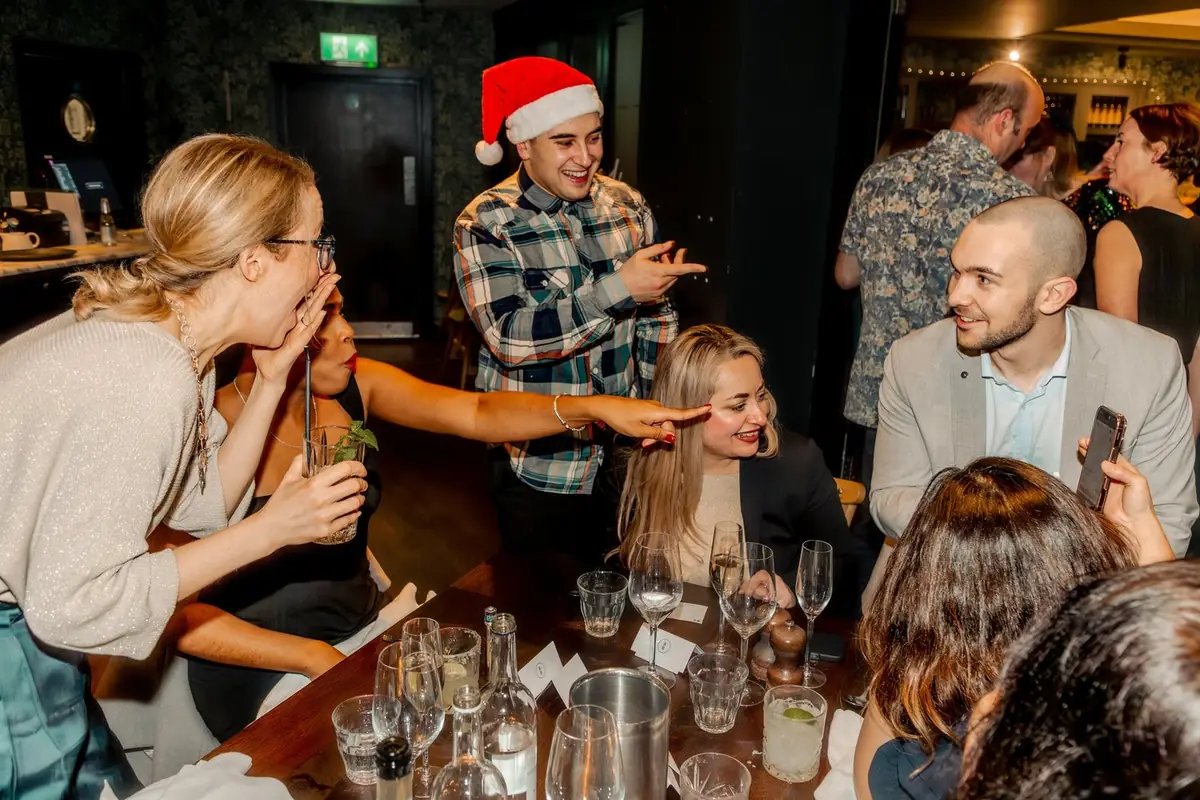 Audience of employees amazed on the close-up magic entertainment at corporate Christmas event.