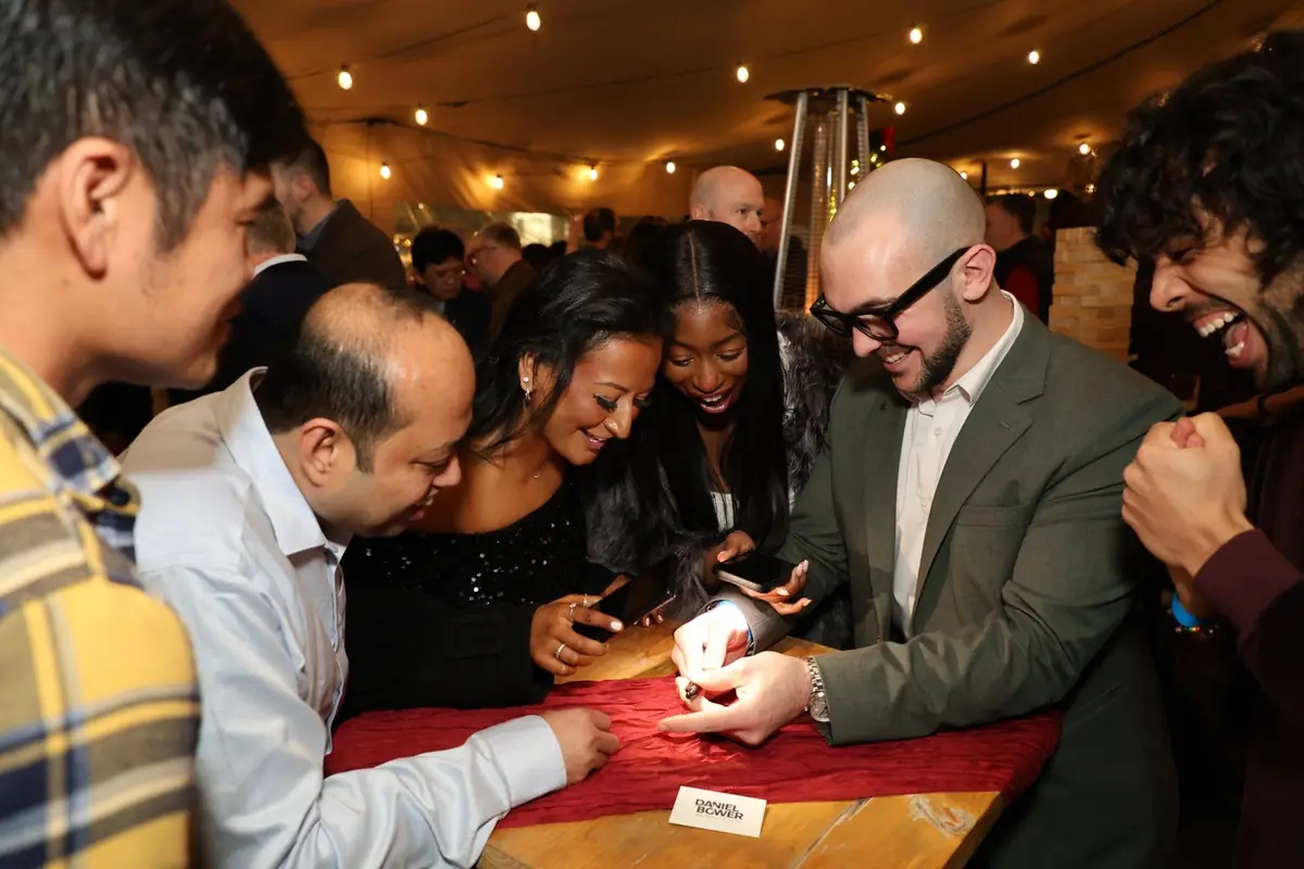 Professional magician entertaining staff with table magic at company holiday event.